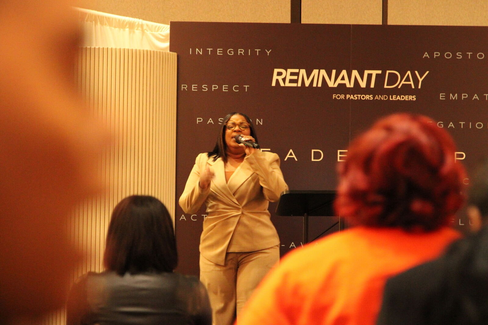 A leader speaking at Remnant Day in front of the event backdrop